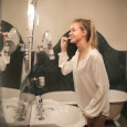 Young blond woman brushing her teeth in front of the mirror