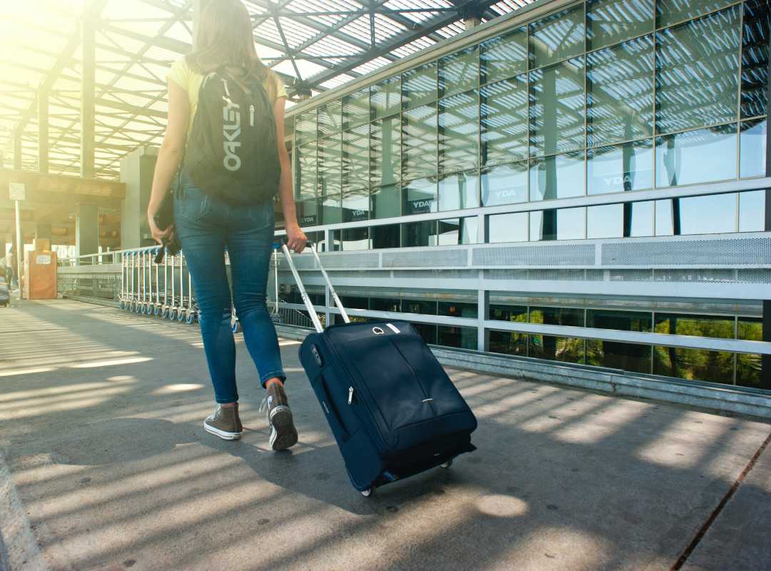 woman with a backpack and suitcase on wheels