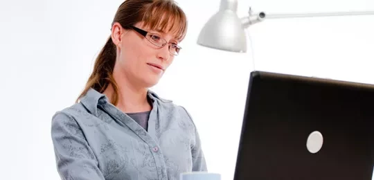 Woman with glasses sitting at a laptop