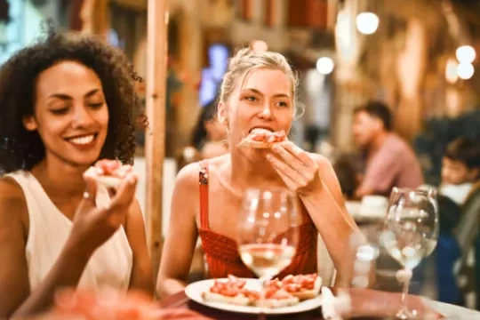 Two female friends eating a pizza at a restaurant
