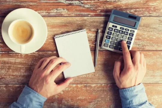 Person sitting at a desk doing calculation using a calculator