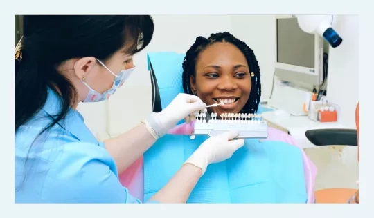 Dentist examining veneer samples with a patient's smile