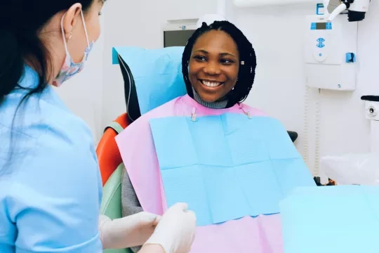 Woman sitting in a dental chair talking to a dentist.