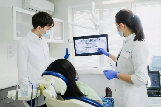 Dentists speaking and showing x-ray to a dental patient